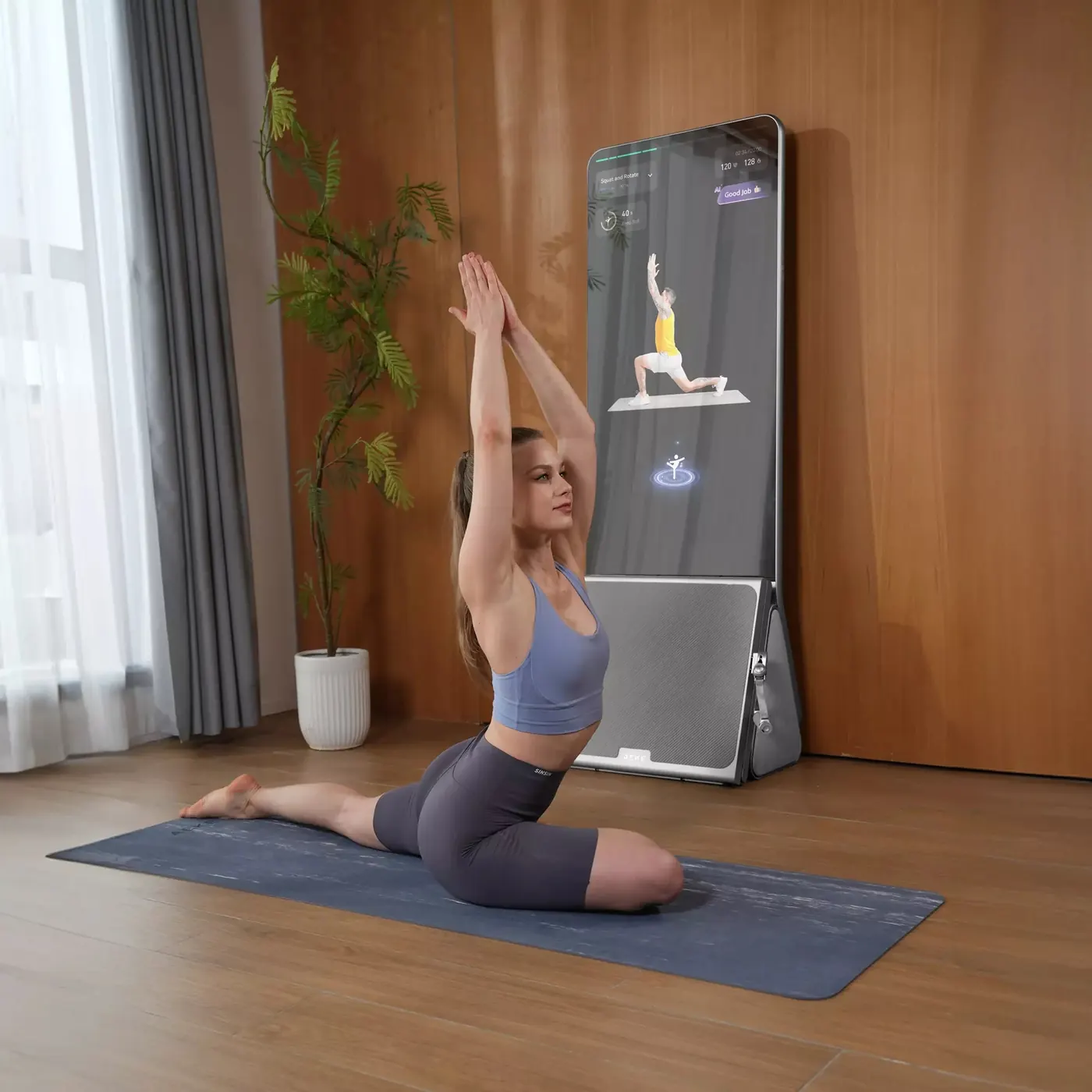 Mulher alongando sobre um tapete de yoga em frente à AEKE K1, numa sala com piso de madeira